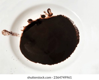Black coffee dregs, spilled on a small saucer melamine , white table background, photo taken in the morning. - Shutterstock ID 2364749961