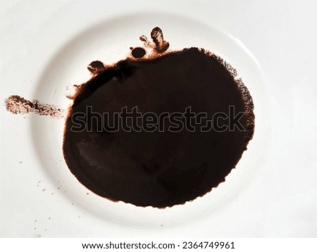 Black coffee dregs, spilled on a small saucer melamine , white table background, photo taken in the morning.