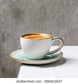 Black coffee espresso with foam in white ceramic cup with saucer standing on white cotton table cloth. Copy space. Square image - Powered by Shutterstock