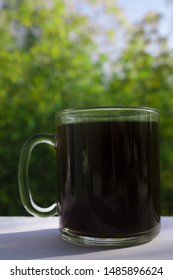 Black Coffee In A Glass Mug. On A White And Green Background. Macro. Side View.