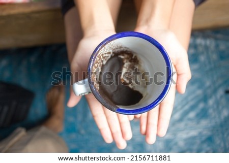 black coffee grounds in a traditional cup or glass when a hand holds it