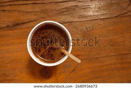 Black coffee from a hot drinks machine from above. Black coffee in a cup with a wooden stirrer. Coffee on the go during a short break.