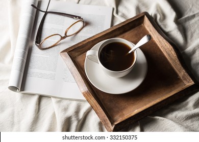 Black Coffee In White Cup With Magazine On The Bed