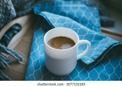 Black coffee in white mug with elegant blue napkin on wooden tray - Shutterstock ID 2077132183