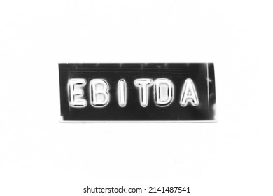 Black color banner that have embossed letter with word EBITDA (abbreviation of earnings before interest, taxes, depreciation and amortization) on white paper background