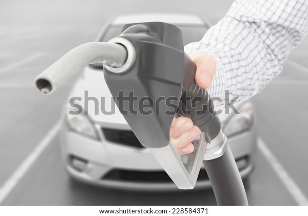 Black\
color fuel pump gun in hand with car on\
background