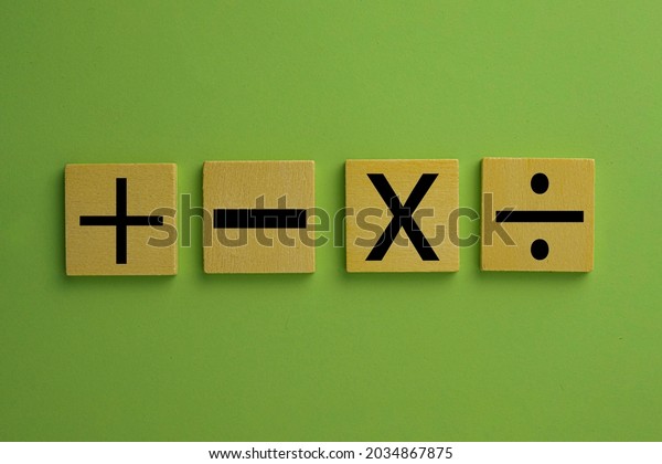 Black\
color of mathematical operations or Plus, minus, multiply, divide\
symbols on wooden cube over green pastel background use for\
mathematic,education,background,school\
concept.