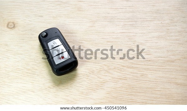 Black color modern car key door opener and keyless\
entry device with autolocking and alarm function on wooden surface.\
Concept of modern car security. Slightly de-focused and close-up\
shot. Copy space