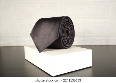 black color polyester fabric necktie rolled isolated over white gift box black and white concept shot 