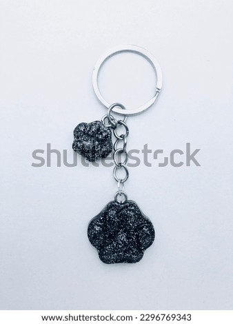 A black colour keytag on a white background. This keytag has two cat hand shape keytags. The inside of the keytags have silver colour glitter powder. This keytag has silver colour keychain also.