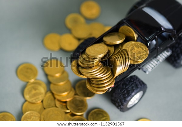 Black colour of miniature car pickup\
truck with stacks of coins on grey background with copy space,\
banking savings money and business finance\
concept.