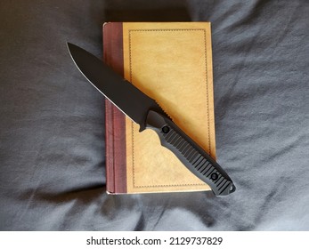 Black Combat Knife On A Book