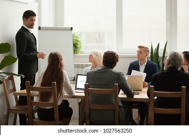 Black Company Ceo In Suit Discussing Business Strategy Presentation At Meeting With Young And Senior Team People In Conference Room, African Manager Presenting New Plan To Project Group In Boardroom