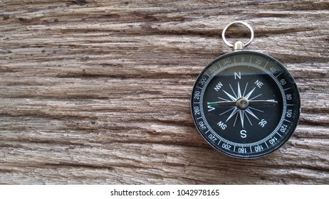 black compass on wooden background - Shutterstock ID 1042978165