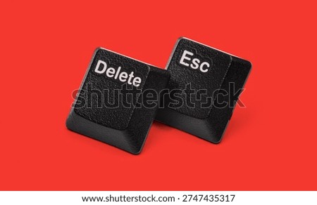 Black computer keyboard Delete and Esc keys isolated on red background. Close up technology concept showing command buttons for cancel, reset, remove, exit, control and digital workflow actions.