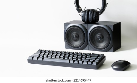 Black Computer Keyboard, Mouse, Headphones And Two Audio Speakers On White Background. Concept Of Audio Recording Studio And Digital Audio Broadcasting. Copy Space. Selective Focus. Daylight