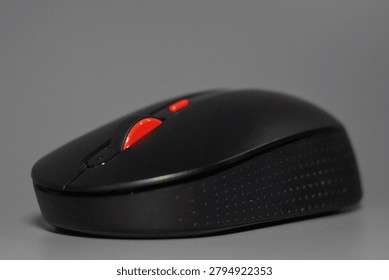 Black computer mouse isolated on a gray background. Modern computer accessory used for work, office tasks, gaming, technology, and digital communication