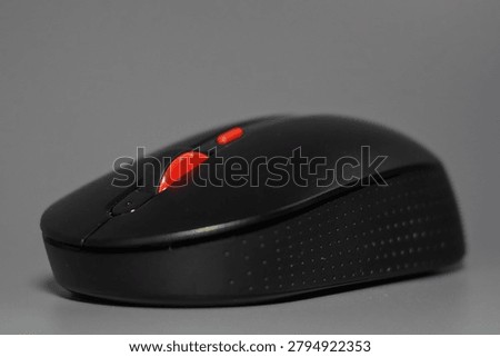 Black computer mouse isolated on a gray background. Modern computer accessory used for work, office tasks, gaming, technology, and digital communication