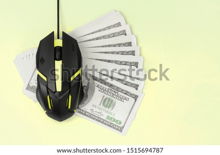 Black computer mouse on many hundred dollar bills