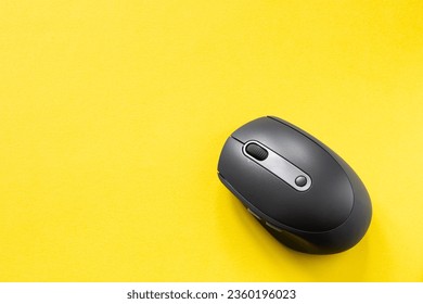 Black computer mouse on yellow background. Wireless optical PC mouse. Wireless technology. Copy space