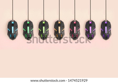 Black computer mouses hang on pastel peach background