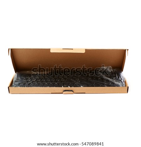 Black computer querty keyboard packed into cardboard box isolated over white background