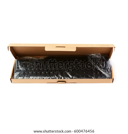 Black computer querty keyboard packed into cardboard box isolated over white background