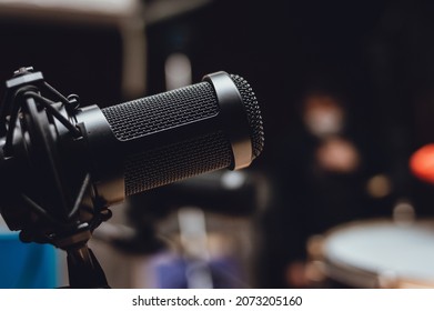 Black Condenser Microphone In A Recording Studio, With A Blurred Music Rehearsal Room In The Background And A Copy Space On The Right, Music Industry Concept.