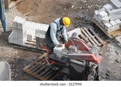 Black Construction Worker Operating A Brick-cutting Machine At A Construction Site