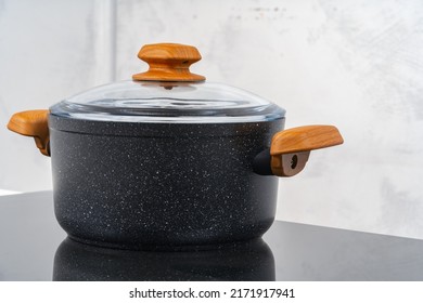 Black Cookware On Induction Stove Against Grey Wall