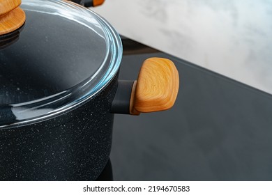 Black Cookware On Induction Stove Against Grey Wall