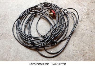 
The Black Cord Coiled In A Loop On The Cement Ground.