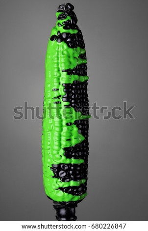 Black corn with pouring green toxic paint on gray background. Fashion food concept.Creative.