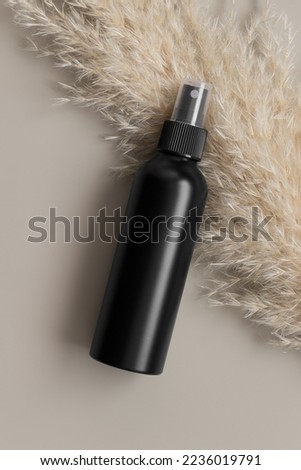 Black cosmetic spray bottle mockup with a pampas on the beige background.