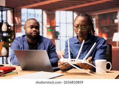 Black couple analyzing network problems and troubleshooting signal loss, adjusting their router placement to optimize internet speed for work and streaming. Struggling with working from home.