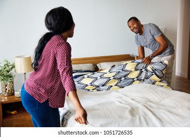 Black Couple Changing Bed Sheet Together