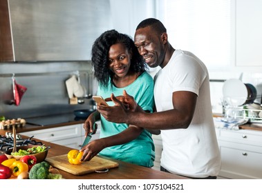 Black couple cooking in the kitchen together - Powered by Shutterstock