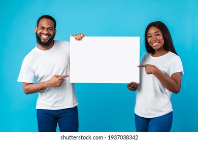 Black couple holding and pointing at blank white advertising placard