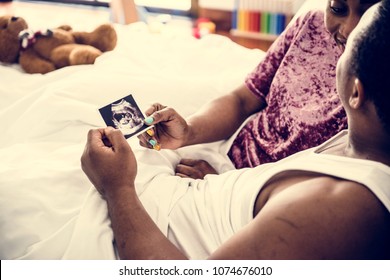 Black Couple Looking At Baby Ultrasound Scan Photo