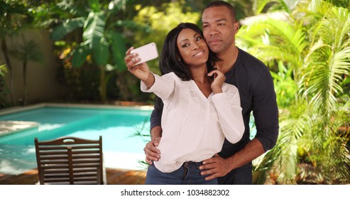 Black couple on vacation in Caribbean taking selfie together by a pool - Powered by Shutterstock