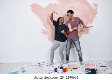 Black couple, painting fun and wall in home with renovation, love and bonding with art. Paint brush, joy and happy people at property with smile for diy and creative project with care and support - Powered by Shutterstock