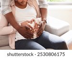 Black couple, pregnant and heart hands on stomach for love, support or feeling baby kick in home. Future parents, hug or touch belly in living room for growth, maternity or commitment in relationship