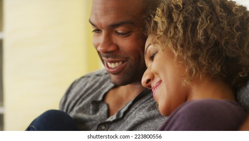 Black Couple Sitting On Couch Smiling