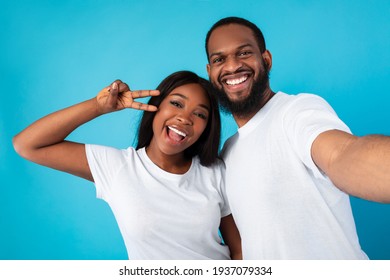 Black couple taking selfie showing victory sign or peace gesture