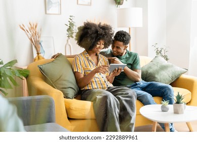 Black couple using tablet on sofa
