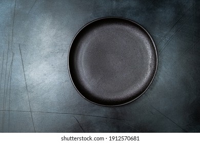 Black craft plate on dark stone table. Top view, copy space, Table setting. background for menu, layout, place for text , recipe background, food flat lay background
