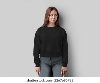 Black cropped sweatshirt template on a beautiful girl, casual textured apparel for design, print, advertising, front view. Mockup of fashion shirt canvas bella, longsleeve isolated on white background