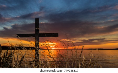 Black cross behind some dry grass stalks with a wonderful sunset in the background.