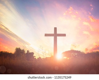 black cross religion symbol silhouette in grass over sunset or sunrise sky - Shutterstock ID 1135175249