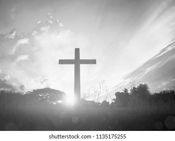 black cross religion symbol silhouette in grass over sunset or sunrise sky - Shutterstock ID 1135175255